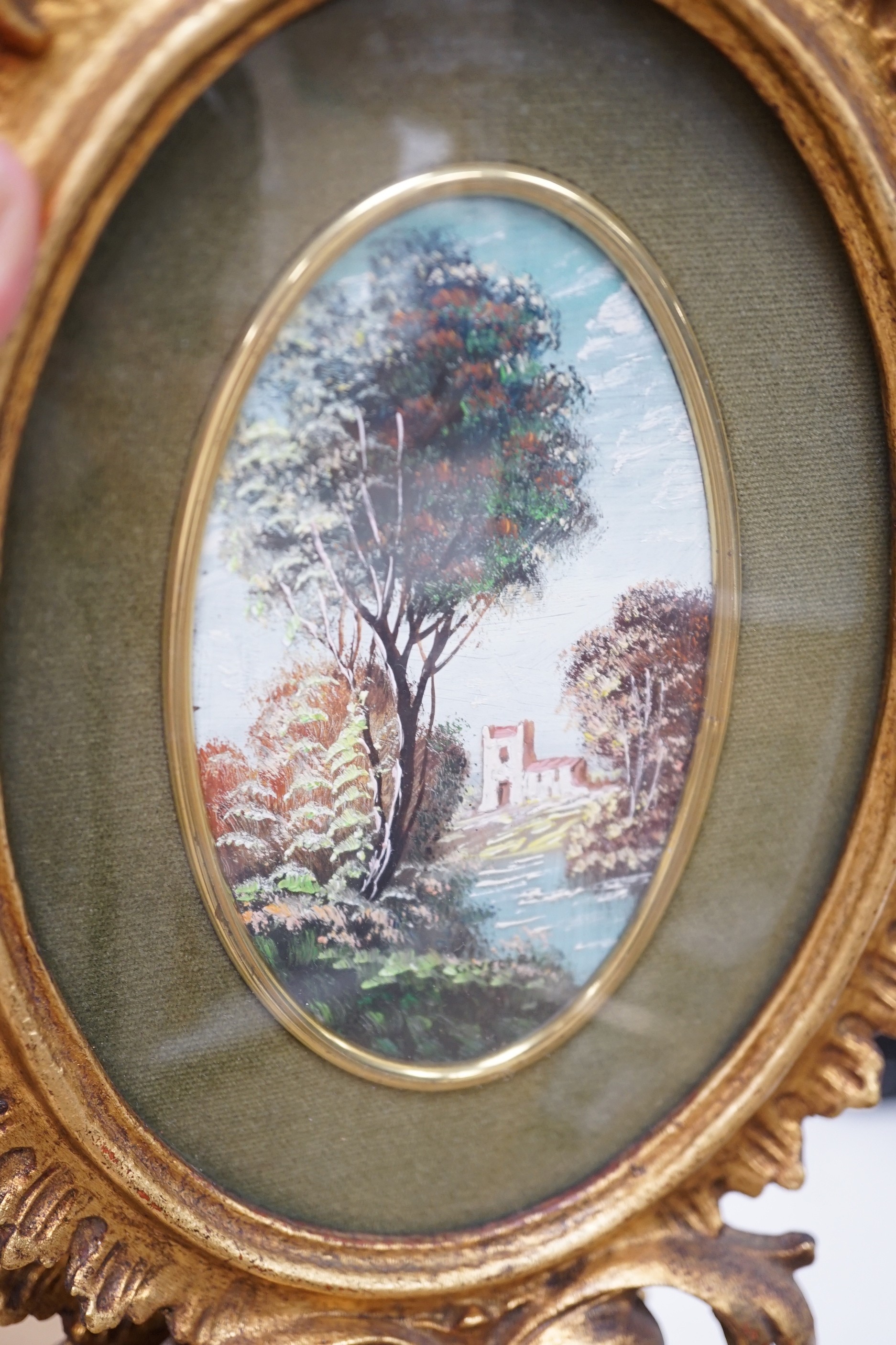 A pair of miniature Italianate landscapes, with pierced, carved oval giltwood frames. 29cm high overall